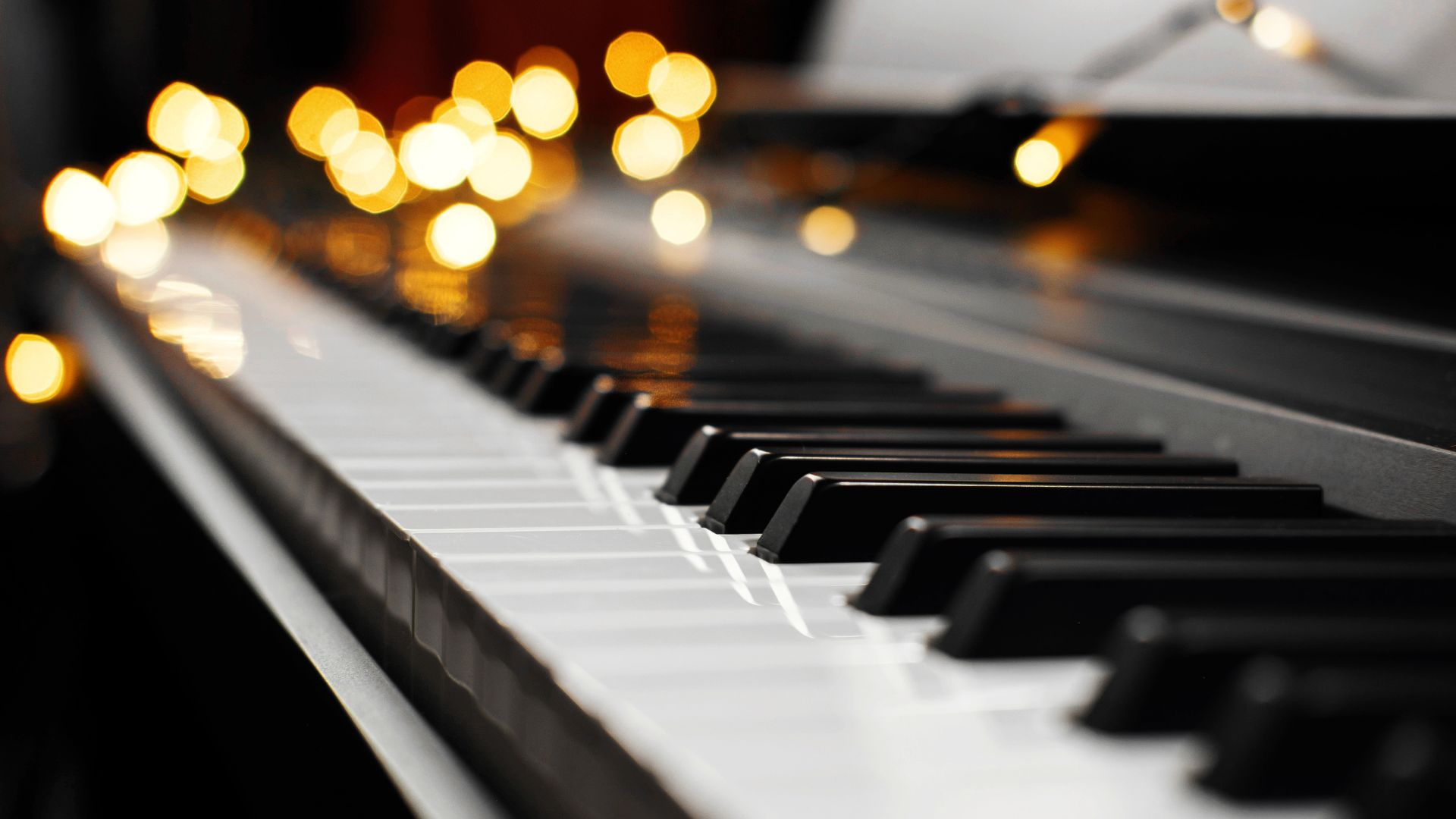 Piano keyboard with blurred warm golden bokeh lights in background
