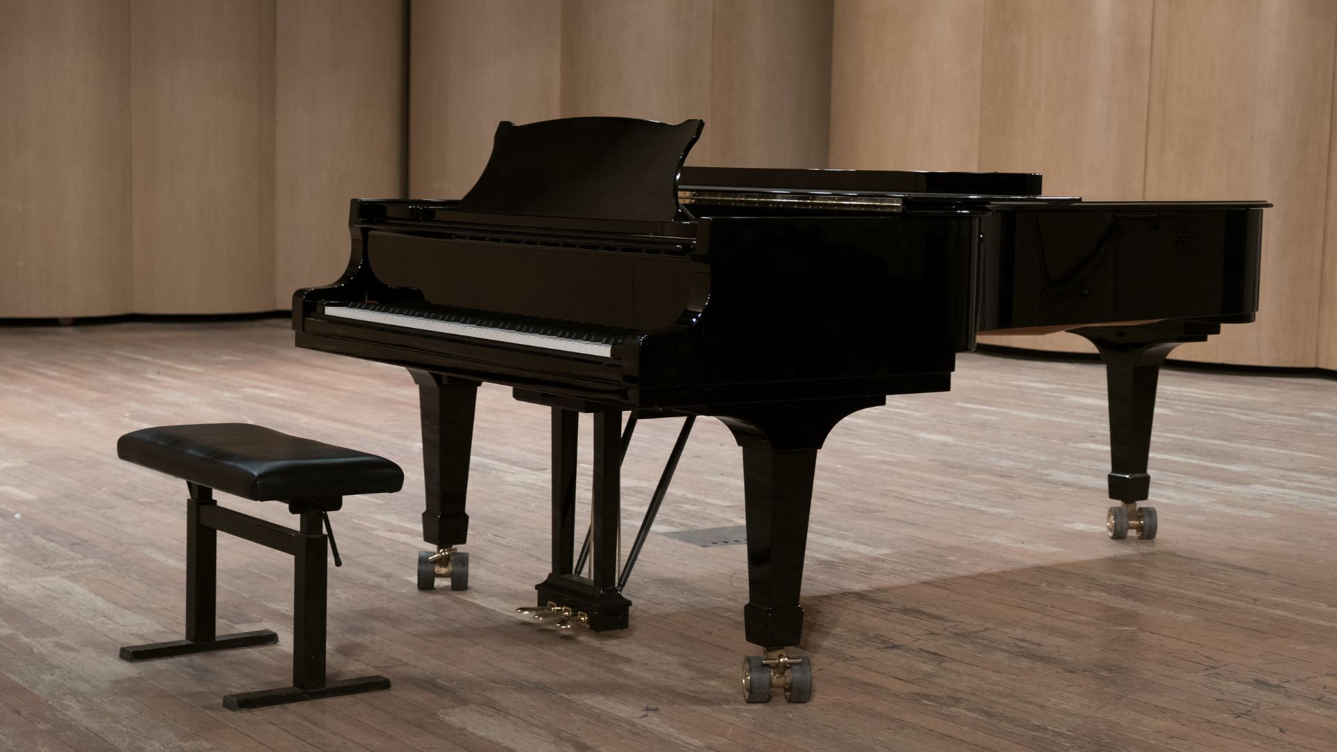 A black piano sitting on top of a hard wood floor