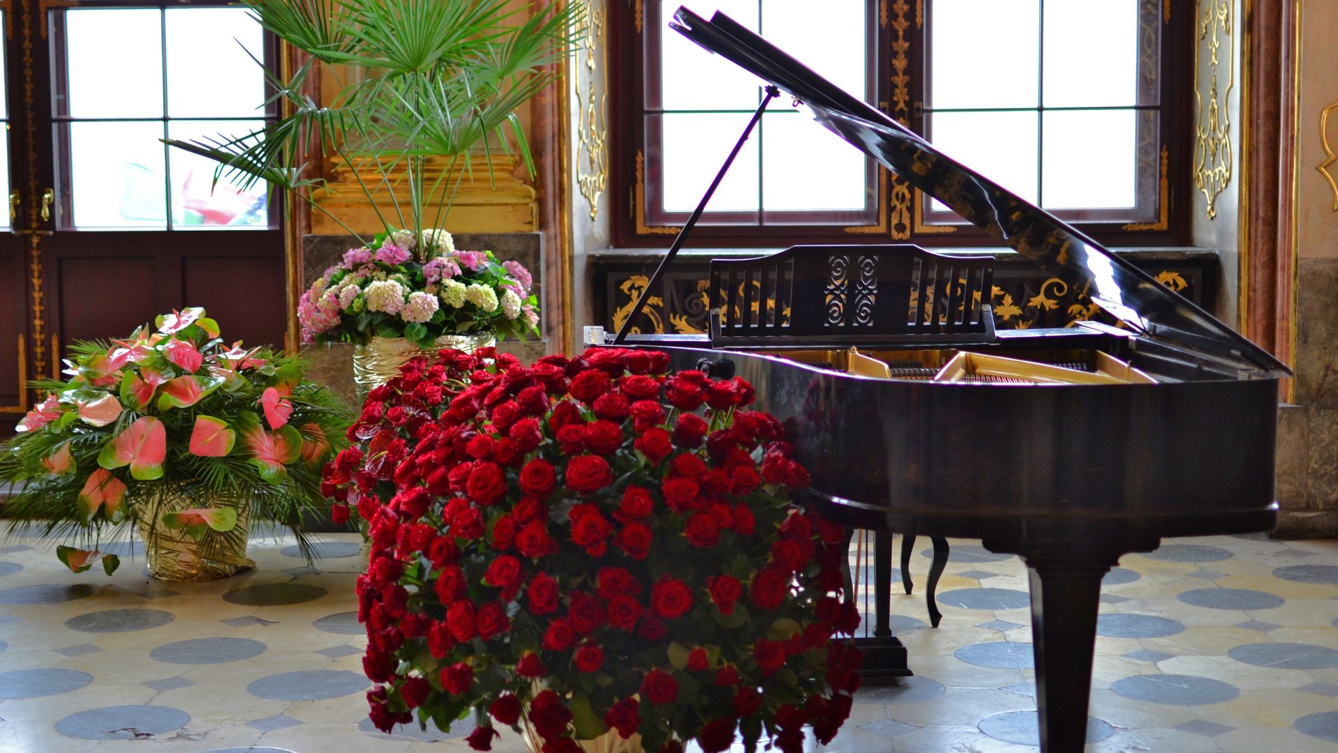 A grand piano and a bouquet of roses in a room
