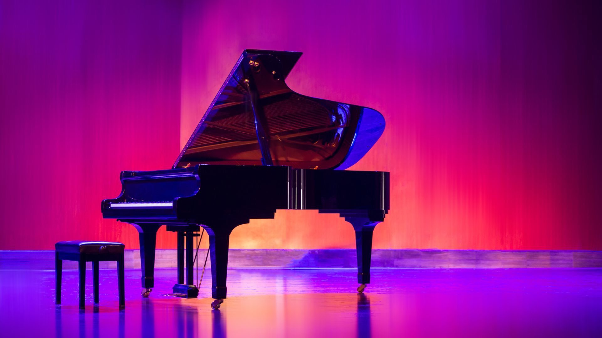 A grand piano sitting on a stage with a stool