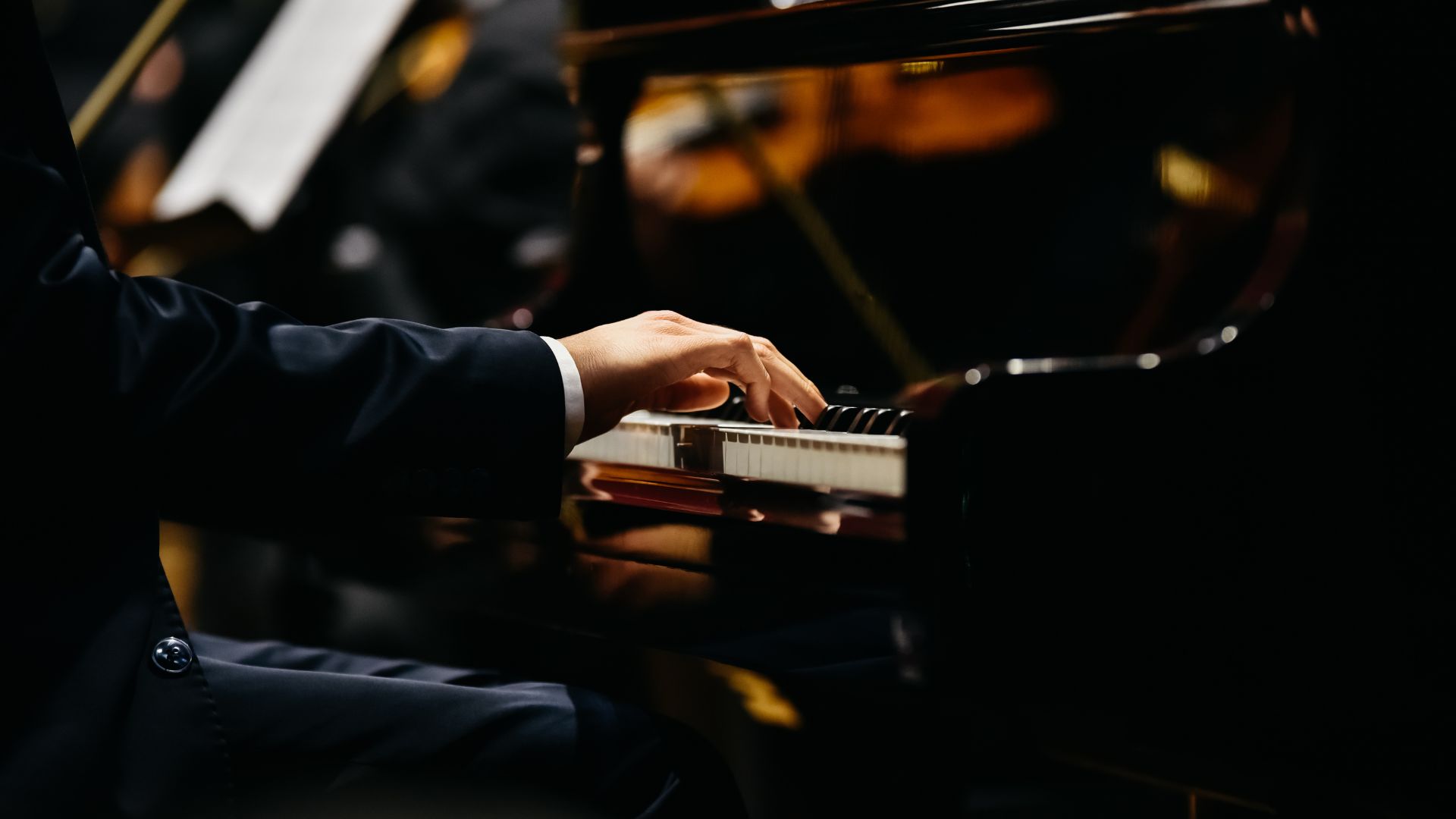 Pianist in formal attire playing grand piano during concert performance